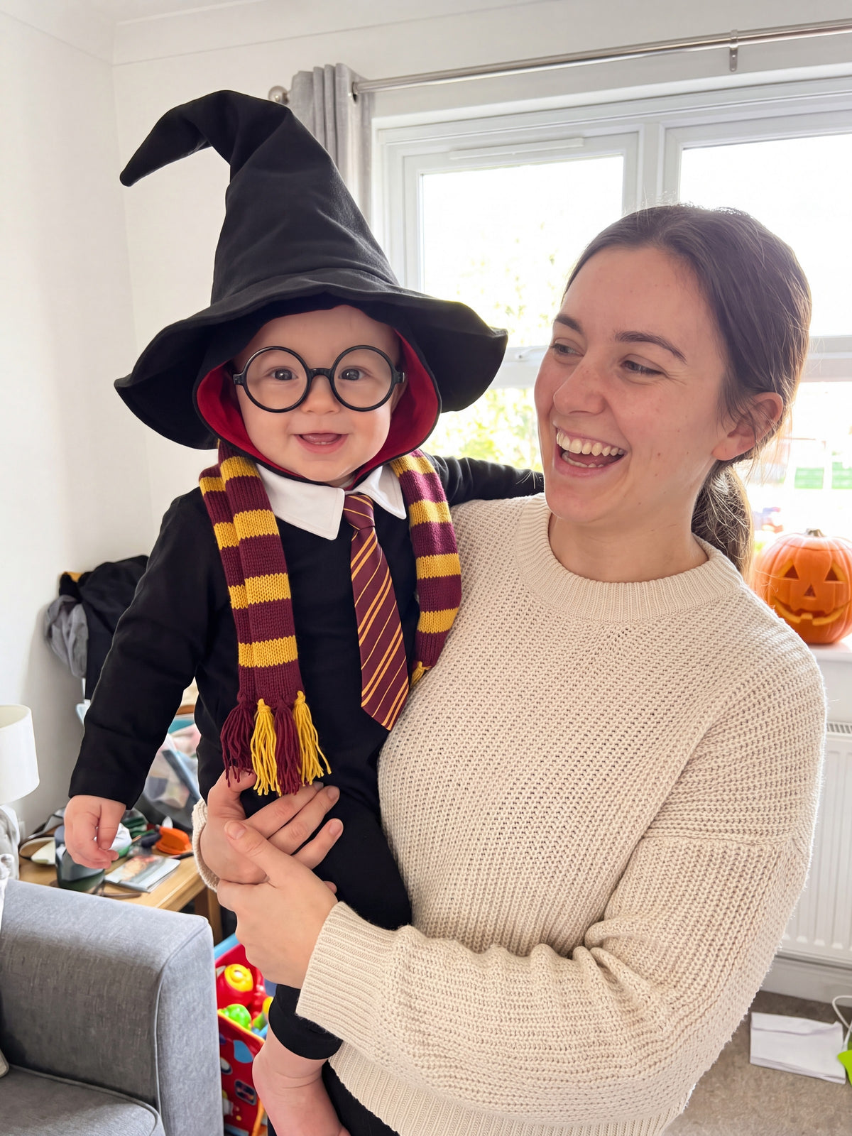 A mum laughing with her baby dressed as a little wizard